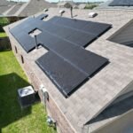 Aerial view of suburban homes in a residential neighborhood with solar panels on rooftop